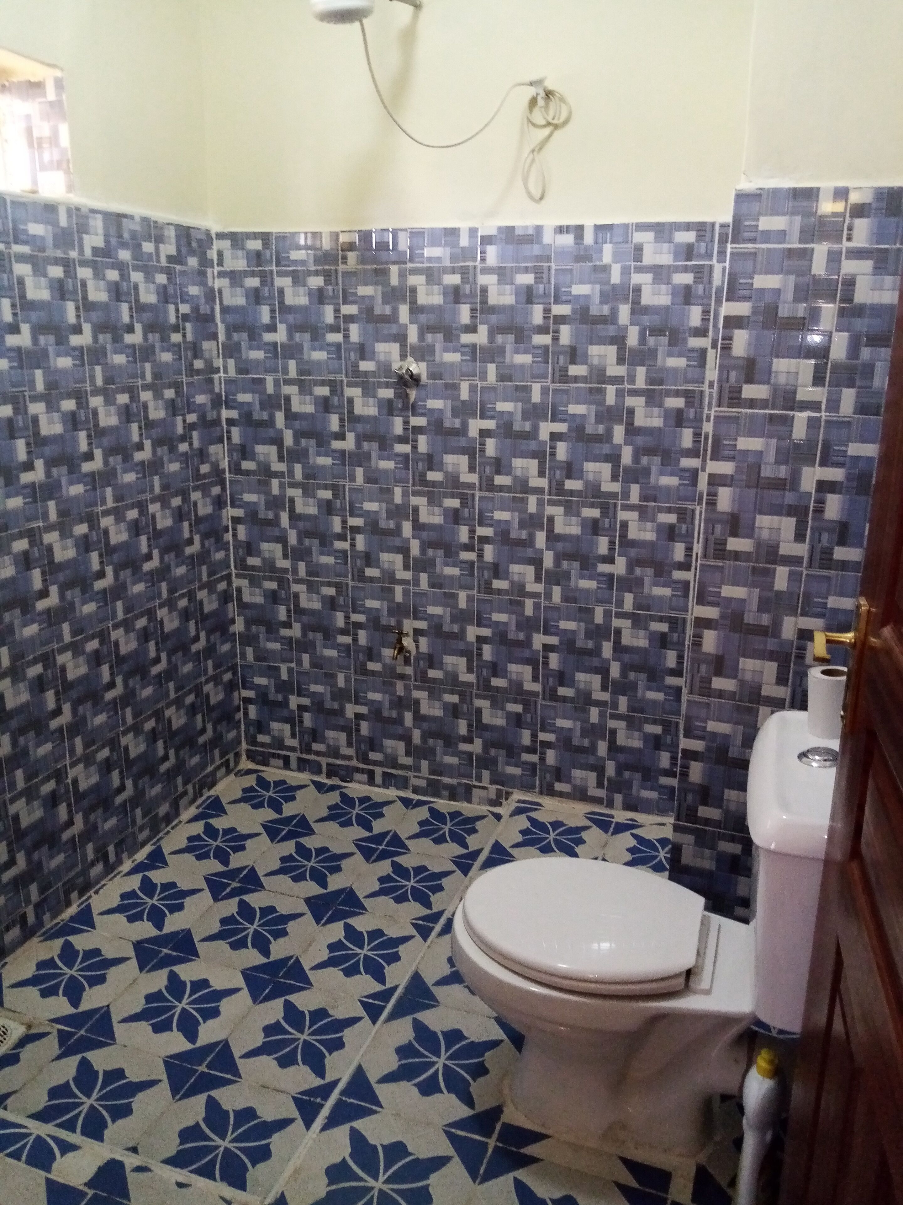 A small bathroom with a toilet, a shower, and tiled walls and floor.