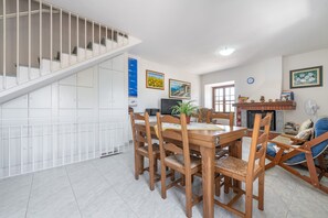Un coin repas avec une table et des chaises en bois, un escalier et une cheminée.