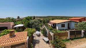 Ein Wohngebiet mit Häusern, einer Terrasse mit Tisch und Stühlen und einem wolkenlosen, blauen Himmel.