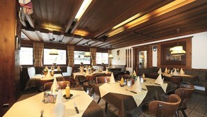 A restaurant with wooden beams, tables set with candles, and a view of the outside.