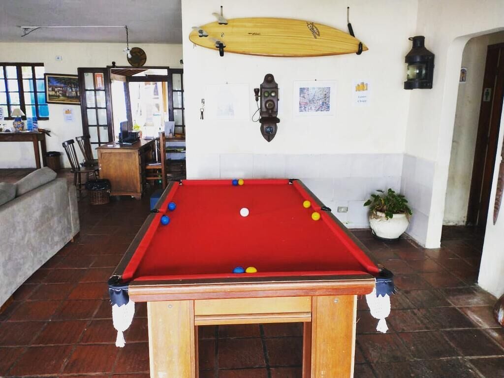 A pool table with balls, a surfboard, and a map on the wall.