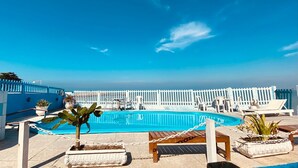 A pool area with a clear blue sky, white poolside chairs, and a white fence. - Pousada Tartaruga (Rio das Ostras)
