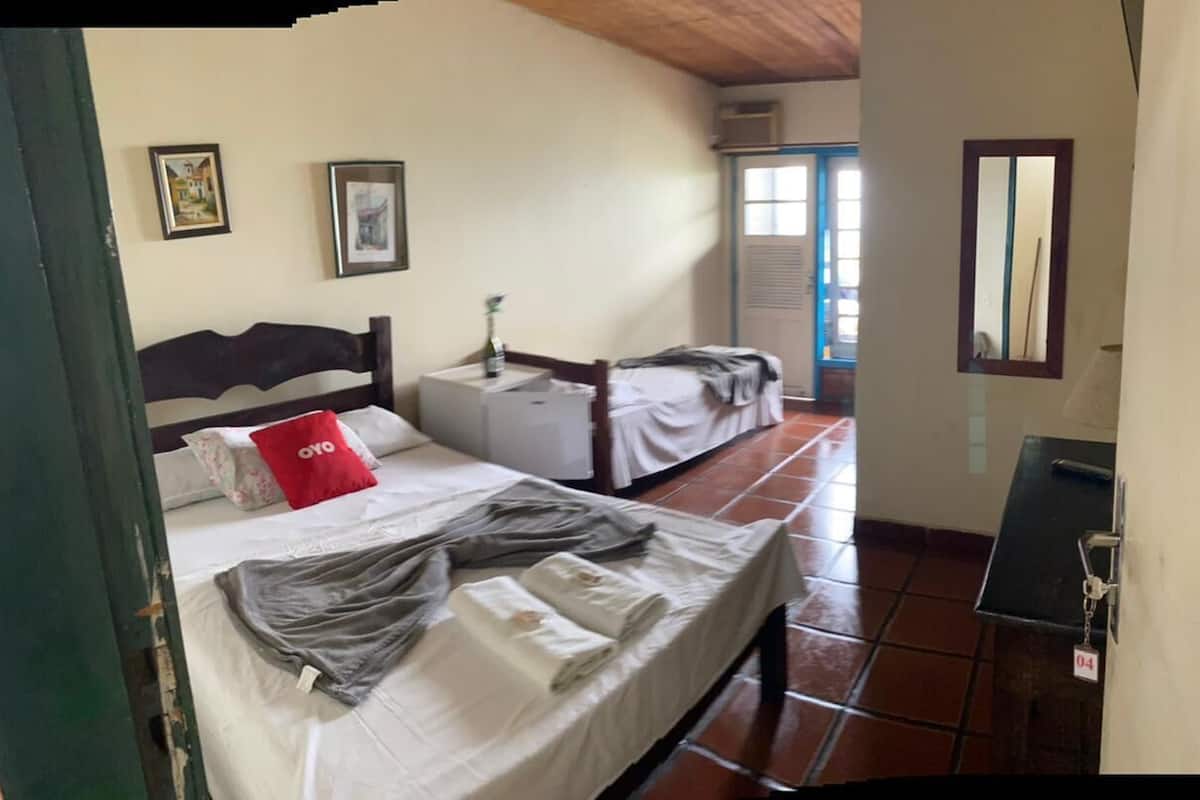 A room with a bed, a bedside table, a small table, and a door with a number.