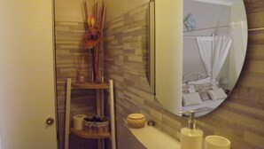 Ein Badezimmer mit Spiegel, Ablage für Pflegeutensilien und Handtuchhalter.