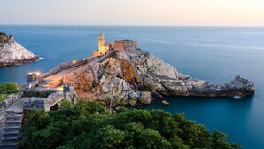 Eine Küstenlandschaft mit historischen Ruinen, einem Turm und Blick auf das Meer.