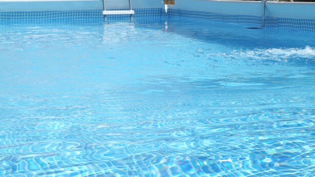 Ein klarer, blauer Pool mit einer gefliesten Kante und einer Leiter zum hineinsteigen.