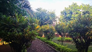 Un chemin pavé, bordé d’une végétation luxuriante et d’arbres, qui mène à un bâtiment situé au loin.