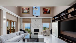 Een moderne woonkamer met een grote flatscreen televisie, een bank, een salontafel en een open haard.