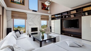 Een moderne woonkamer met een grote televisie, comfortabele zithoek en uitzicht op de oceaan.