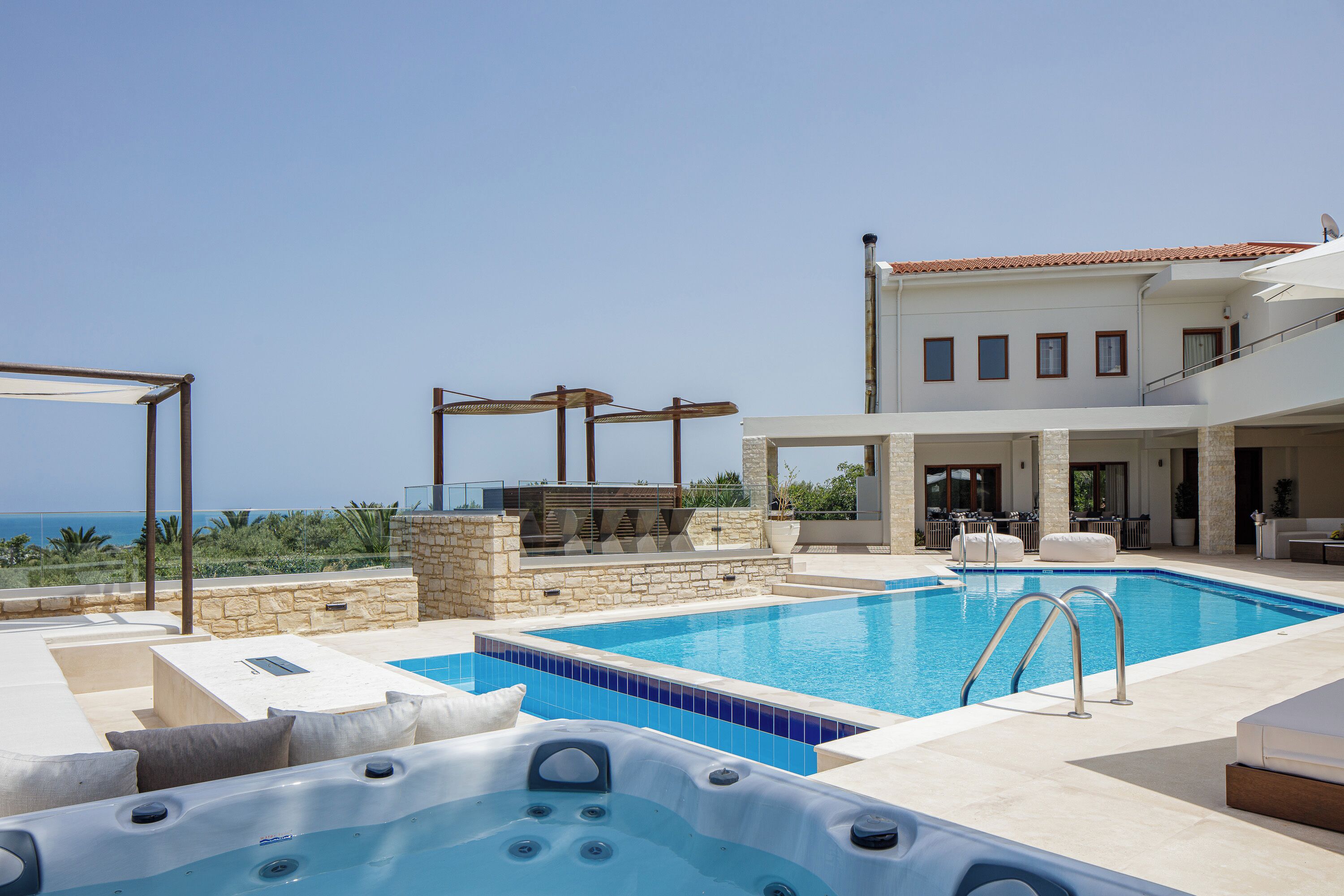 En swimmingpool med jacuzzi, udendørs siddepladser og havudsigt.