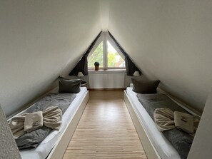 A small attic bedroom with two bunk beds, a wooden floor, and a window with a view of greenery outside. - Suite Jutta 9a OR with balcony (SO) - Usedom Suites 09***, beach 100 m (Karlshagen)
