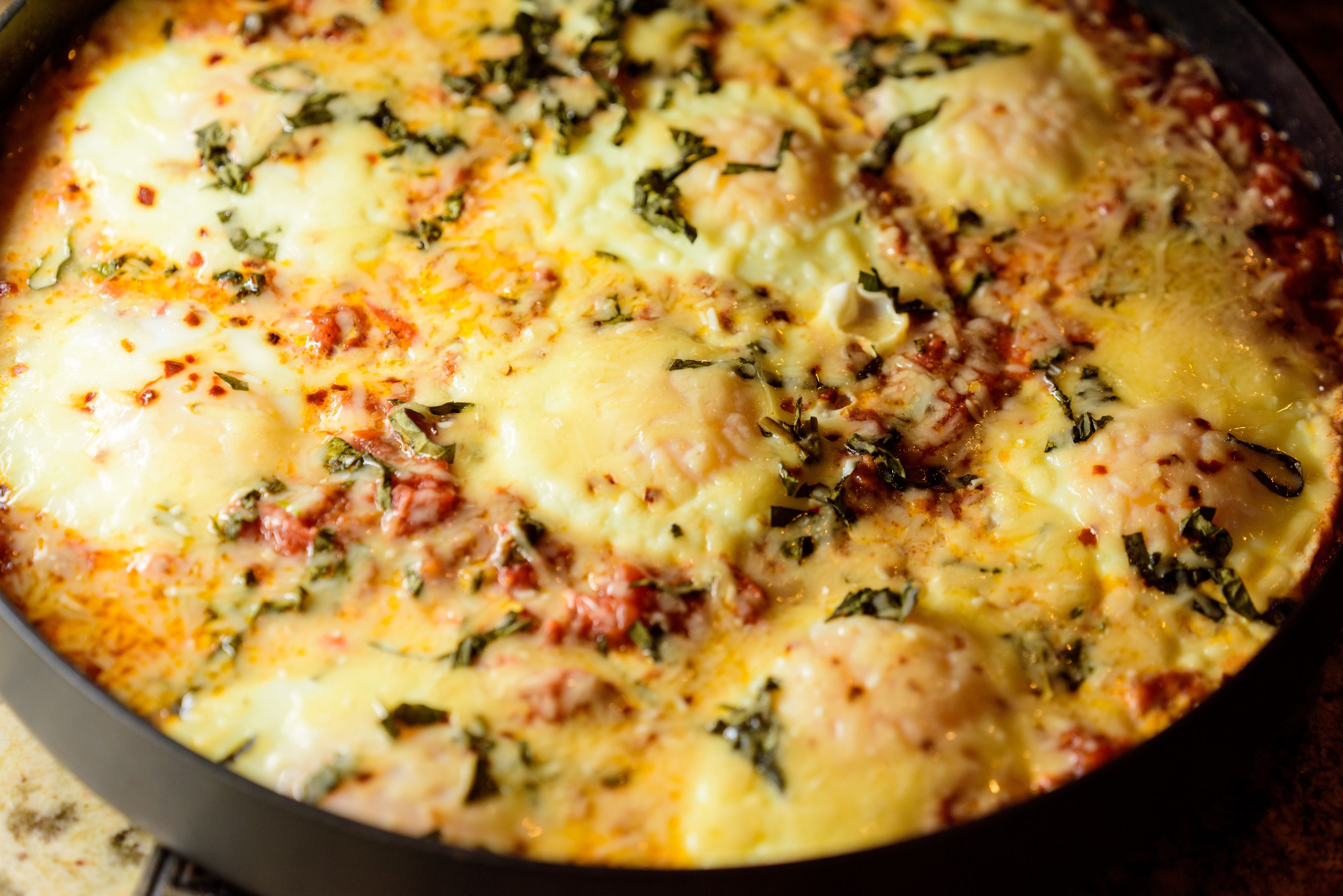 A close-up of a dish with melted cheese and herbs.