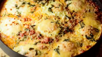 A close-up of a dish with melted cheese and herbs.