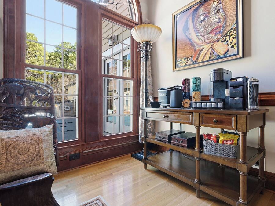 Una habitación con un amplio ventanal de arco, una estación de café, un tapete estampado y una obra de arte enmarcada en la pared.
