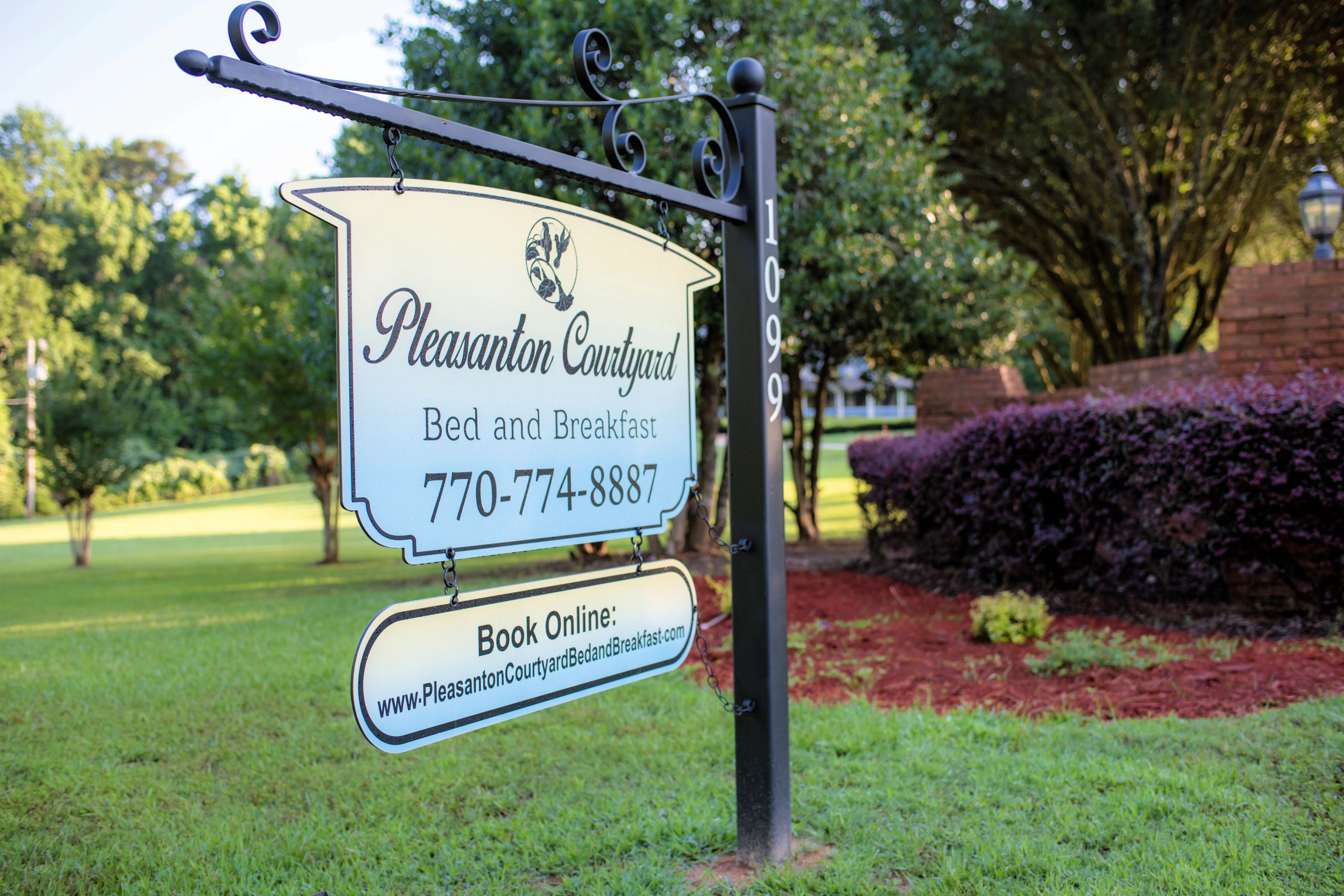 A sign for Plaisant Courtyard Bed and Breakfast with a contact number and an online booking URL.