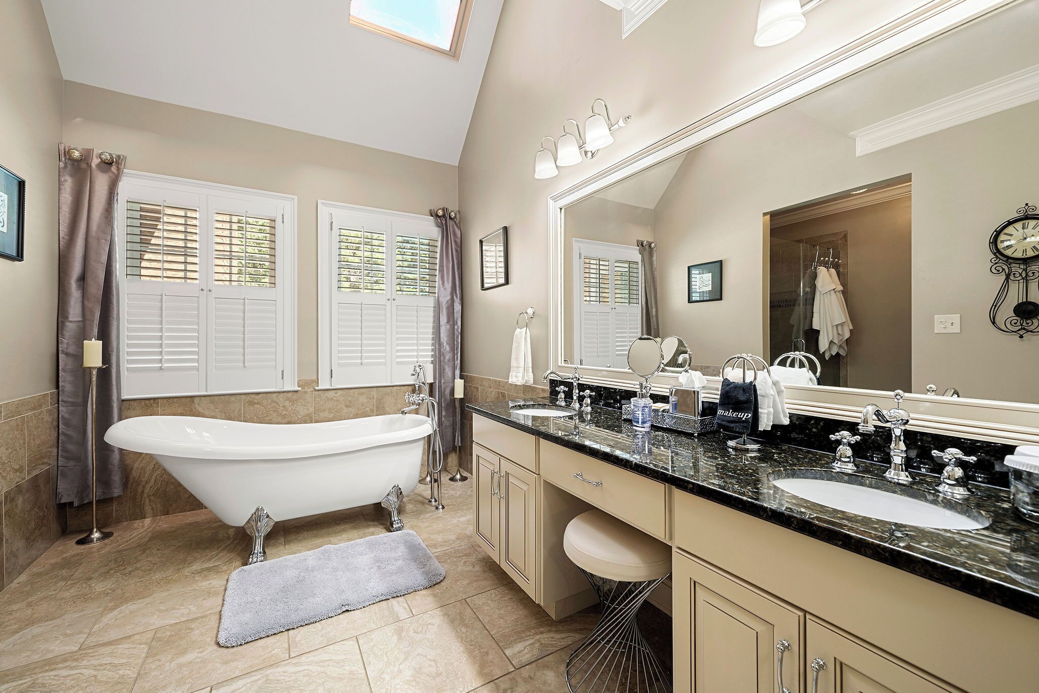 Une salle de bain moderne avec une baignoire sur pieds, un meuble-lavabo avec deux vasques et un grand miroir.