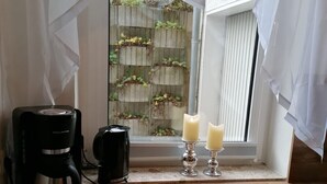 A kitchen with a coffee maker, two candles, and a view of a brick wall with plants. - Central vacation apartment, barrier-free access, please contact us (Braunlage)