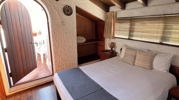 Ein Schlafzimmer mit einem Bett, einem Holzkopfstück und einem Fenster mit Jalousien.