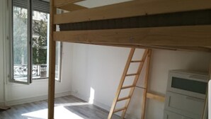 A room with a bunk bed, a ladder, and a white dresser.