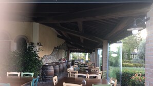 An outdoor patio with wooden tables and chairs, stone walls, and a view of a garden. - Cottage  (Orciano pisano)