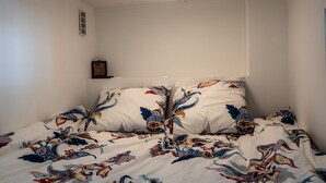 Ein Schlafzimmer mit einem Bett, das mit einer farbenfrohen, gemusterten Tagesdecke ausgestattet ist.