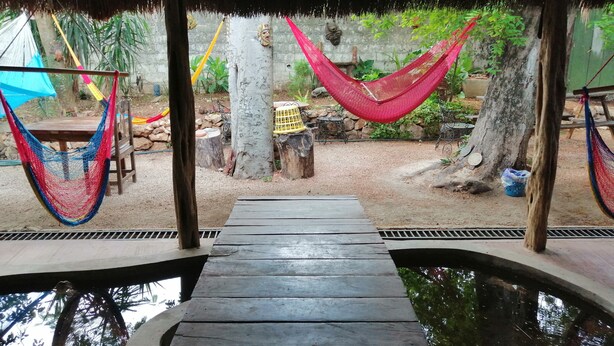 Eine Holzterrasse führt zu einem Pool mit einem überdachten, strohgedeckten Dach.