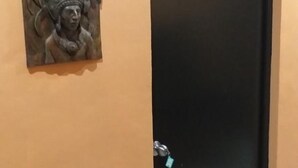 Eine schwarze Tür mit der Nummer 3, ein Schlüssel daran und eine HolzSchnitzerei an der linken Wand.