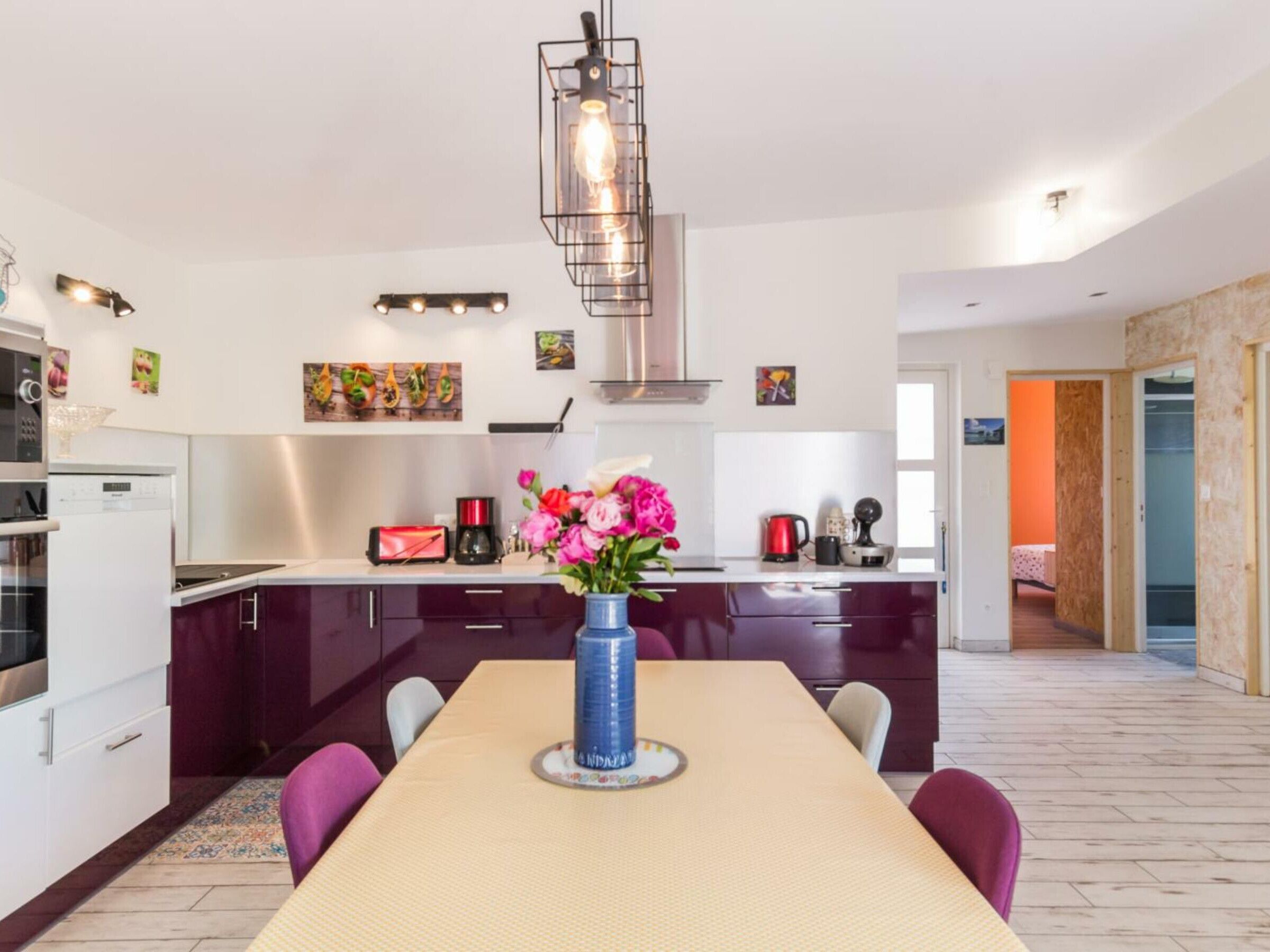Une cuisine moderne avec des meubles de couleur sombre, un îlot central et un coin repas comprenant une table et des chaises.