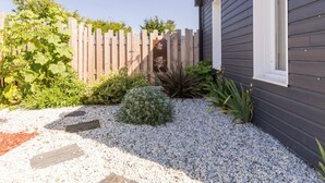 Ein Garten mit Holzzaun, Kiesweg und verschiedenen Pflanzen.