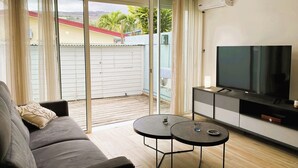 Ein Wohnzimmer mit einer Couch, einem Fernseher und zwei kleinen Tischen.