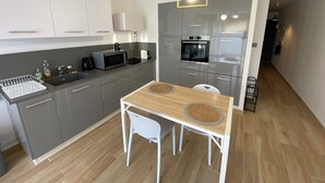Eine moderne Küche mit grauen Schränken, einer Mikrowelle, einem Backofen und einem Esstisch mit zwei Stühlen.