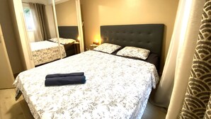 Ein Schlafzimmer mit einem großen Bett, einem Spiegel, einem Nachttisch und einem Kopfteil.