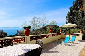 A patio with a table and chairs, a view of the sea, and potted plants. - Nice 3-star apartment with sea view French Riviera (Rayol-Canadel-sur-Mer)