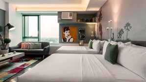 A modern hotel room with a large bed, a sofa, a colorful rug, and a city view. - Posh Entrata SOHO Suite-- Festival Mall view (Alabang, Muntinlupa City)