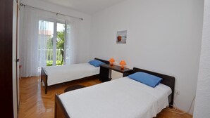 Ein Zimmer mit zwei Betten, einem kleinen Tisch mit Lampen und einem Fenster mit Blick auf Grünflächen.
