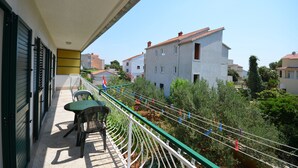 Ein Balkon mit Tisch und Stühlen und Blick auf umliegende Gebäude, mit grüner Brüstung.