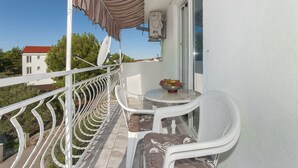 A balcony with white chairs, a small table with a bowl of fruit, and a satellite dish. - Apartments Karleusa (Rogoznica)