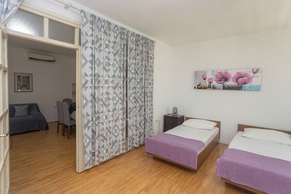 Une chambre avec deux lits, un rideau à motifs, un tableau et un bureau avec une chaise.