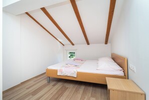 Ein Schlafzimmer mit einem hölzernen Bett, einem kleinen Nachttisch und einem Fenster mit Blick auf Grünflächen.