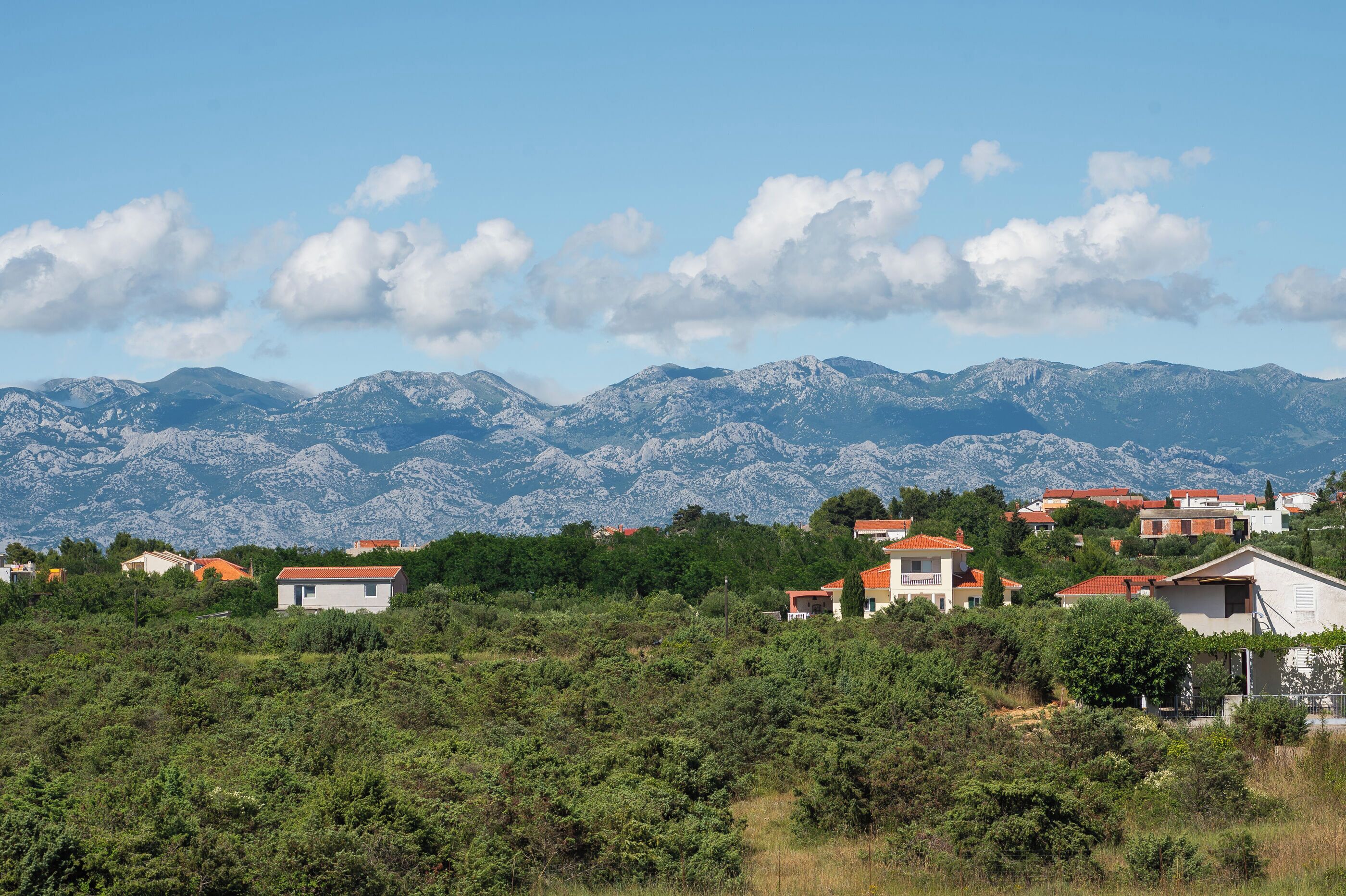 A mountainous landscape with houses in the foreground and a clear sky.