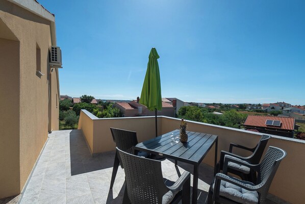 Ein Balkon mit Tisch, Stühlen und einem grünen Sonnenschirm.