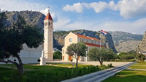 Una iglesia con un campanario y una bandera, rodeada de vegetación y montañas.