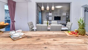 Un comedor con una mesa de madera, sillas y una bandeja de frutas.