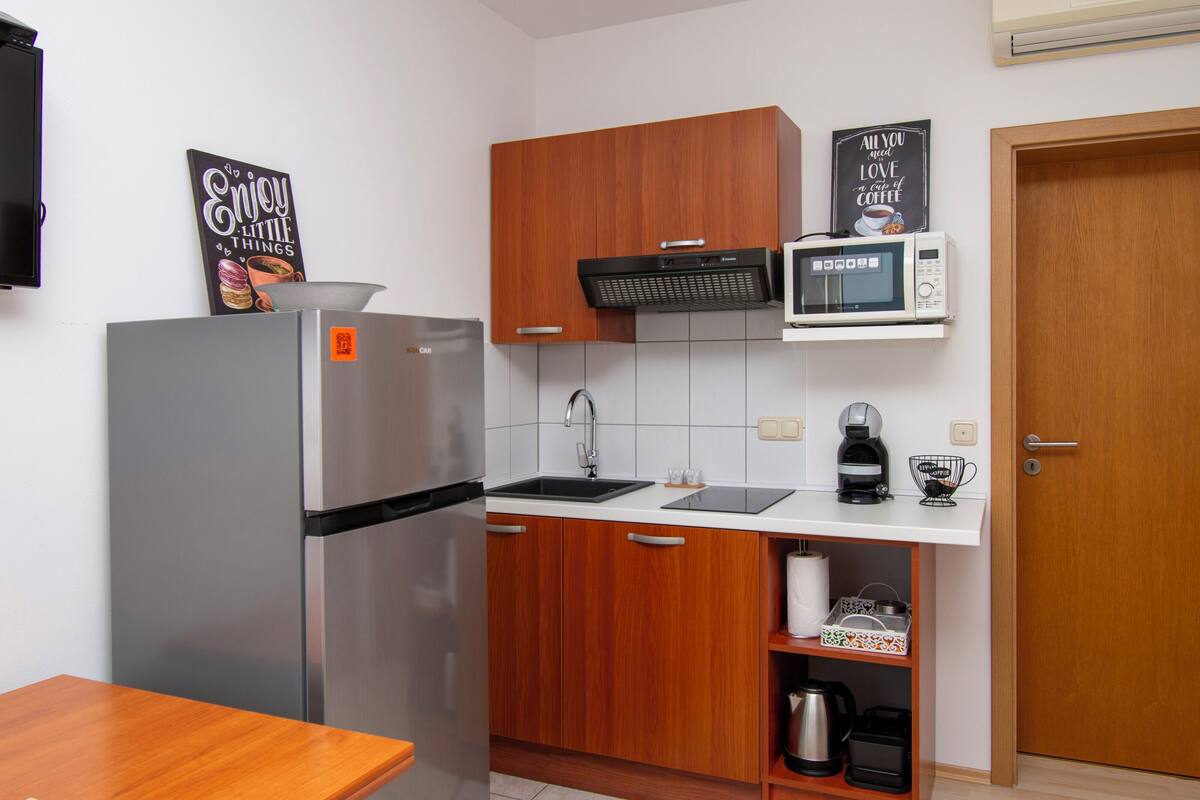 Eine kleine Küche mit Kühlschrank, Mikrowelle, Spüle und Holzschränken.