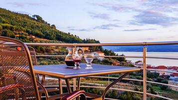 A balcony with a table and chairs, overlooking a scenic view of a lake and hills.