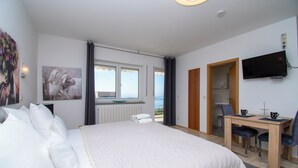A bedroom with a bed, a desk, a chair, a television, and artwork on the walls. - Apartment and Rooms Ana (Podstrana)
