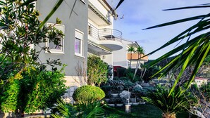 A multi-story building with a balcony, surrounded by well-maintained gardens and various plants. - Apartment and Rooms Ana (Podstrana)