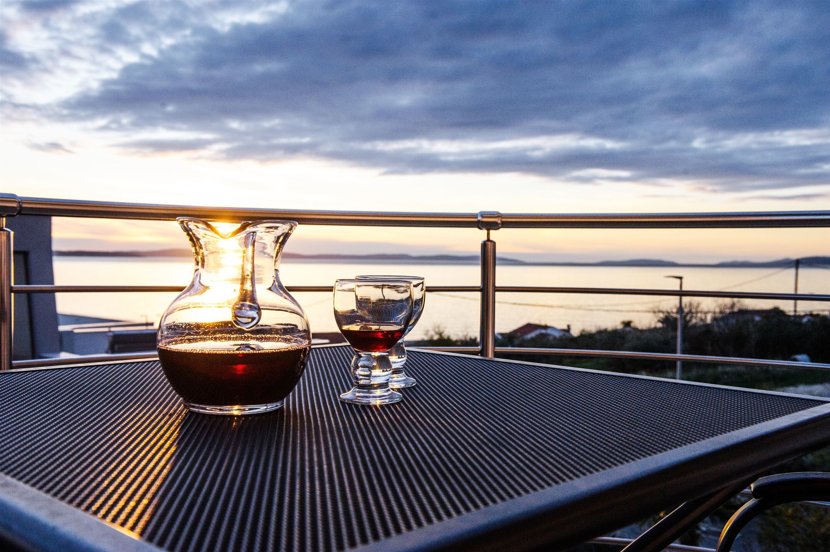 A table with a bottle and a glass on a balcony overlooking a scenic view.