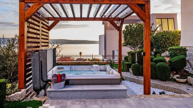 A hot tub under a wooden pergola with a view of the sea. - Apartment and Rooms Ana (Podstrana)