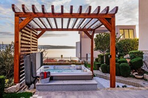 A hot tub under a wooden pergola with a view of the sea. - Apartment and Rooms Ana (Podstrana)